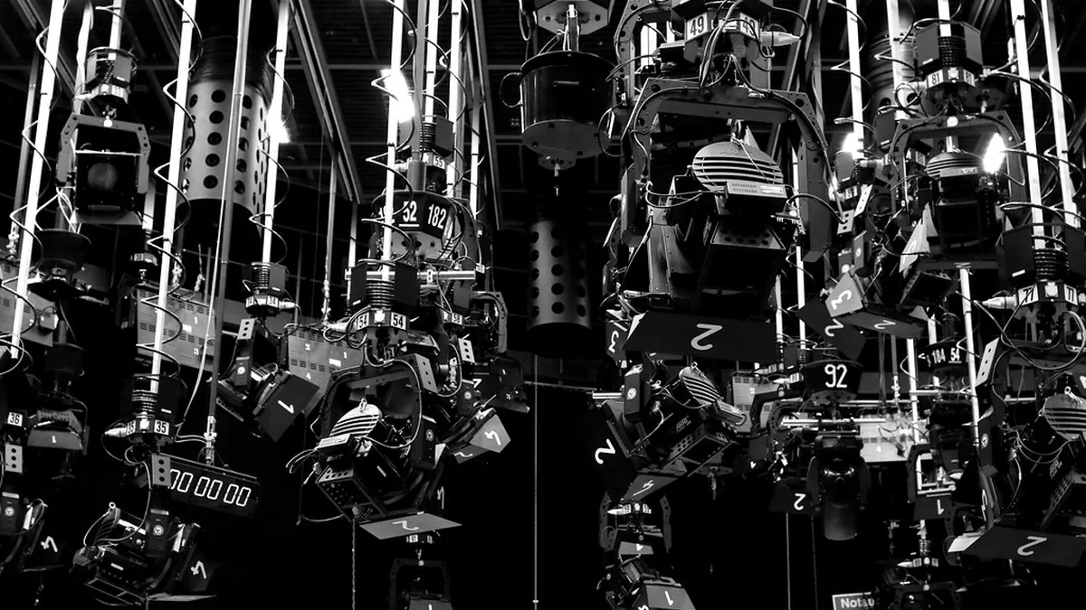 Rows of stage floodlights hanging from the ceiling of a TV studio